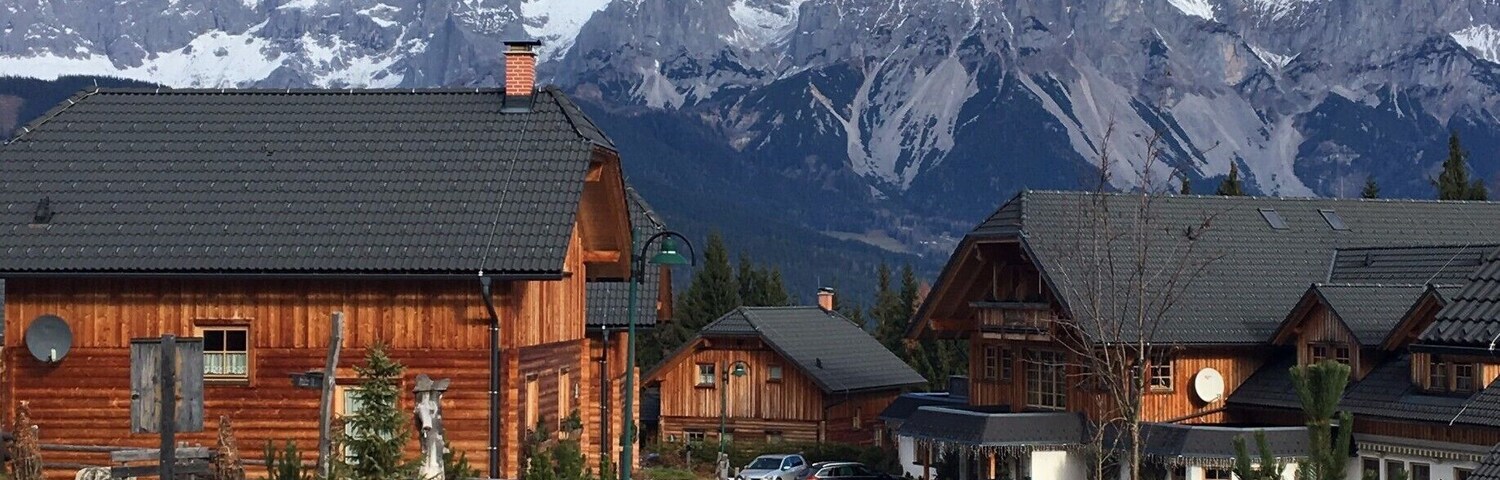 A wooden cabin with a mountain backdrop.