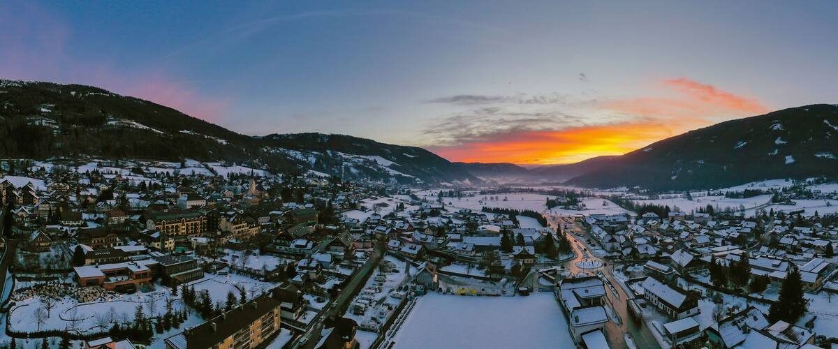 A snow-covered town with a sunset over mountains.