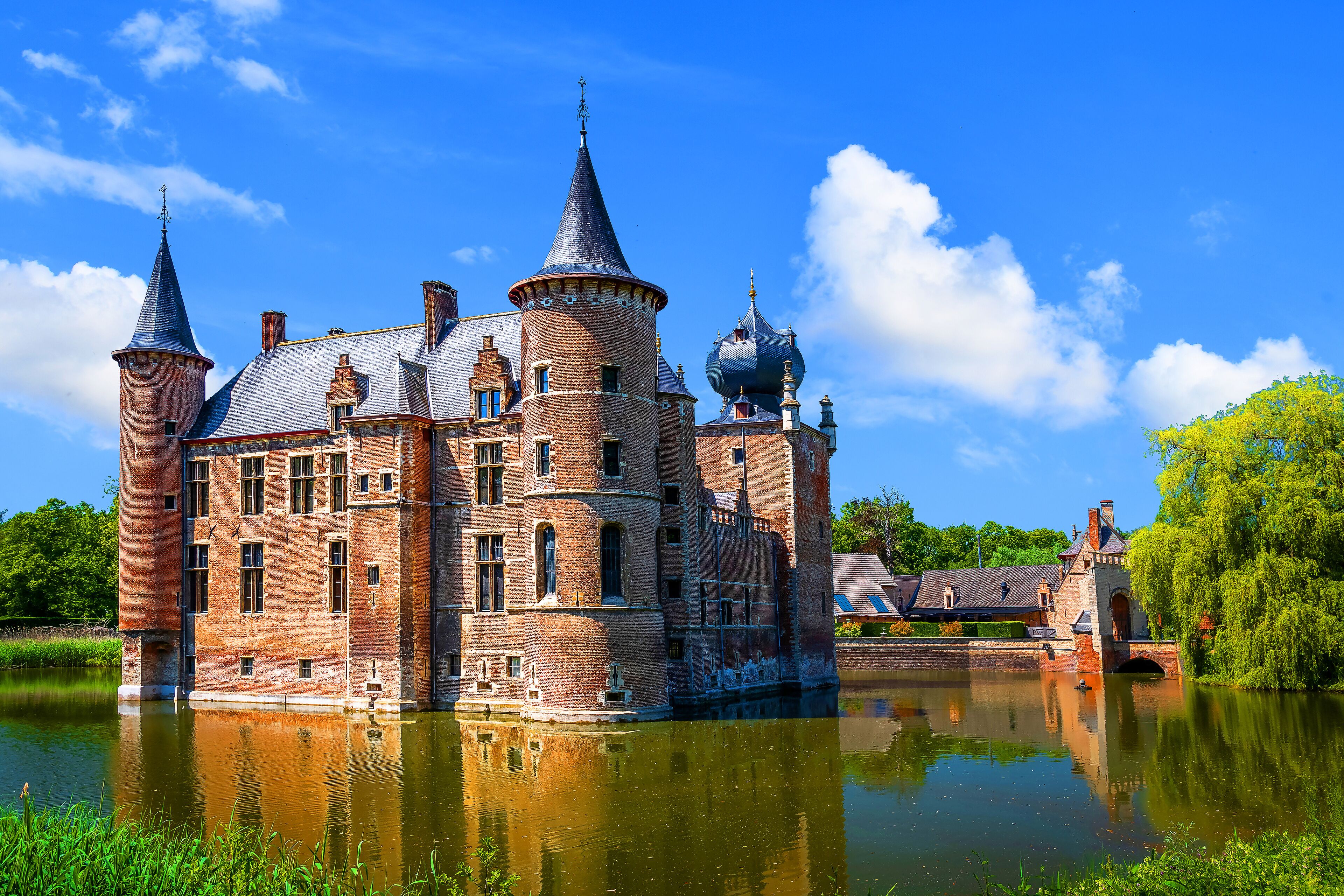 A historic castle with multiple towers and domes, situated by a calm river.