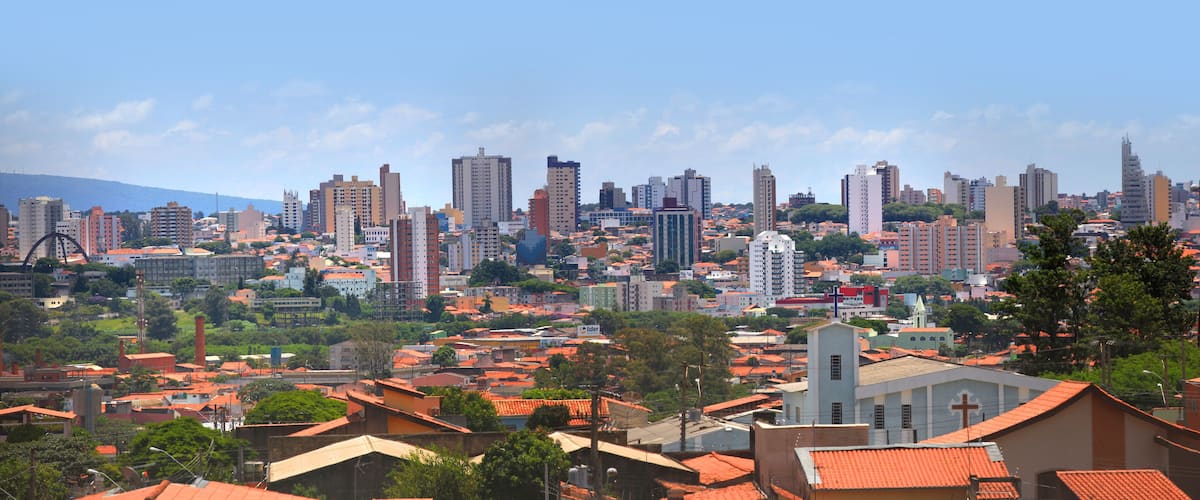A cityscape with a mix of high-rise buildings and smaller residential structures, a prominent church, and a hilly backdrop.
