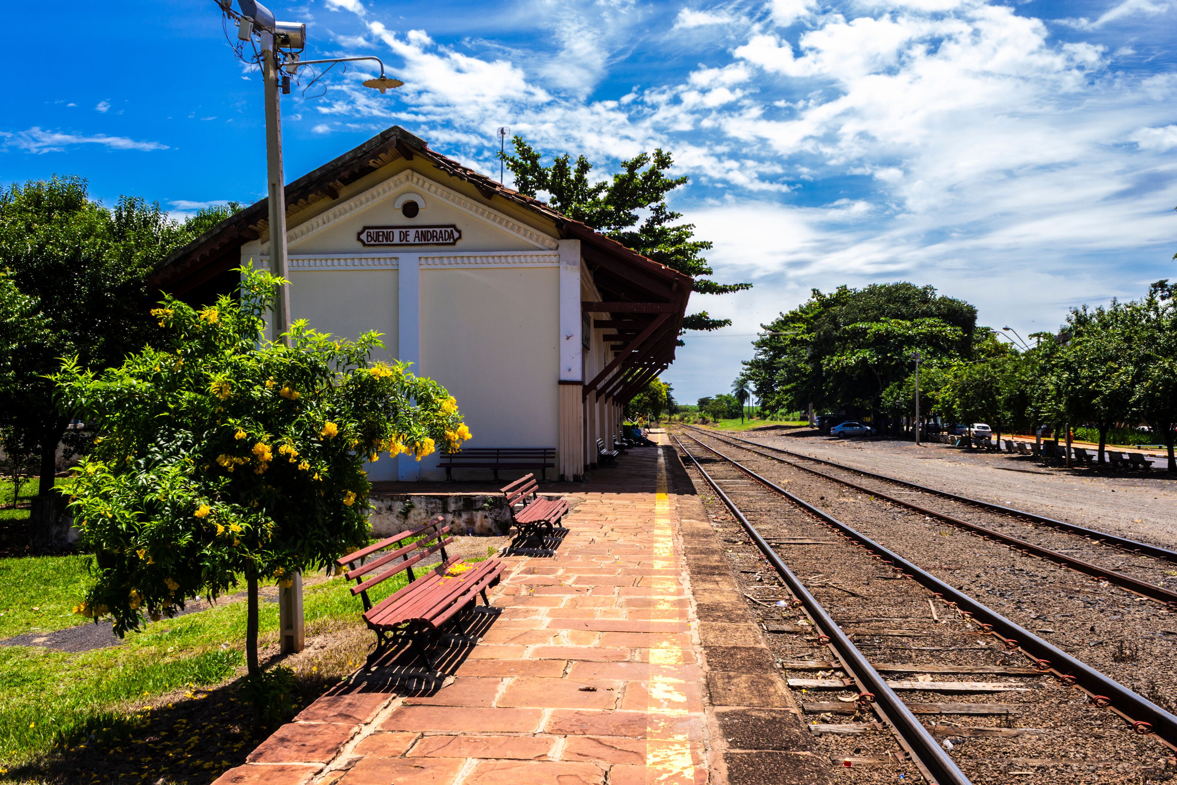 A train station with a white building labeled "BUENOS DE ANDRADA," benches, and tracks.