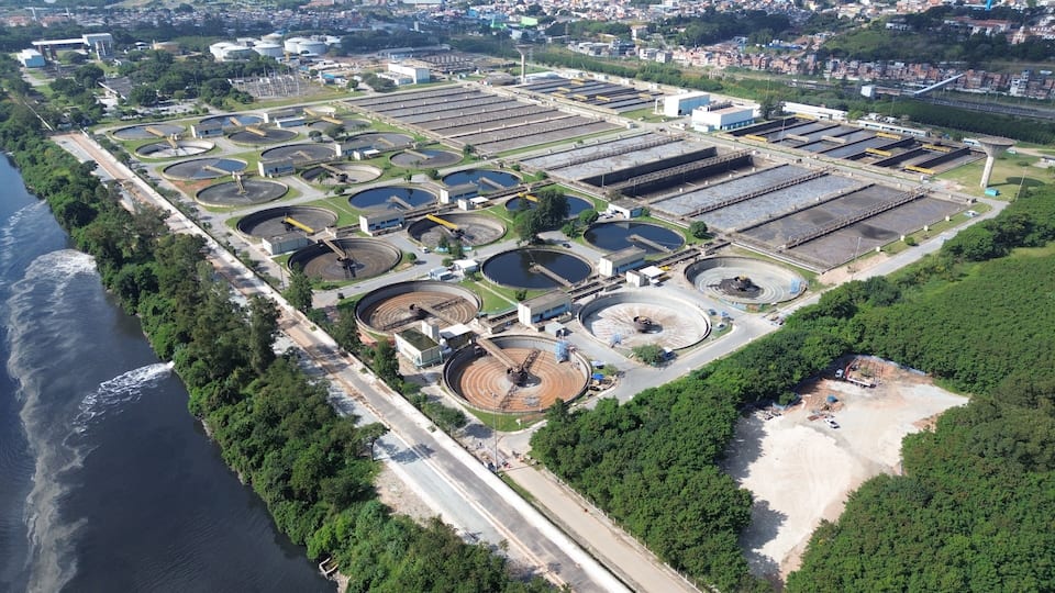 An industrial complex with multiple circular tanks and rectangular structures, adjacent to a river.