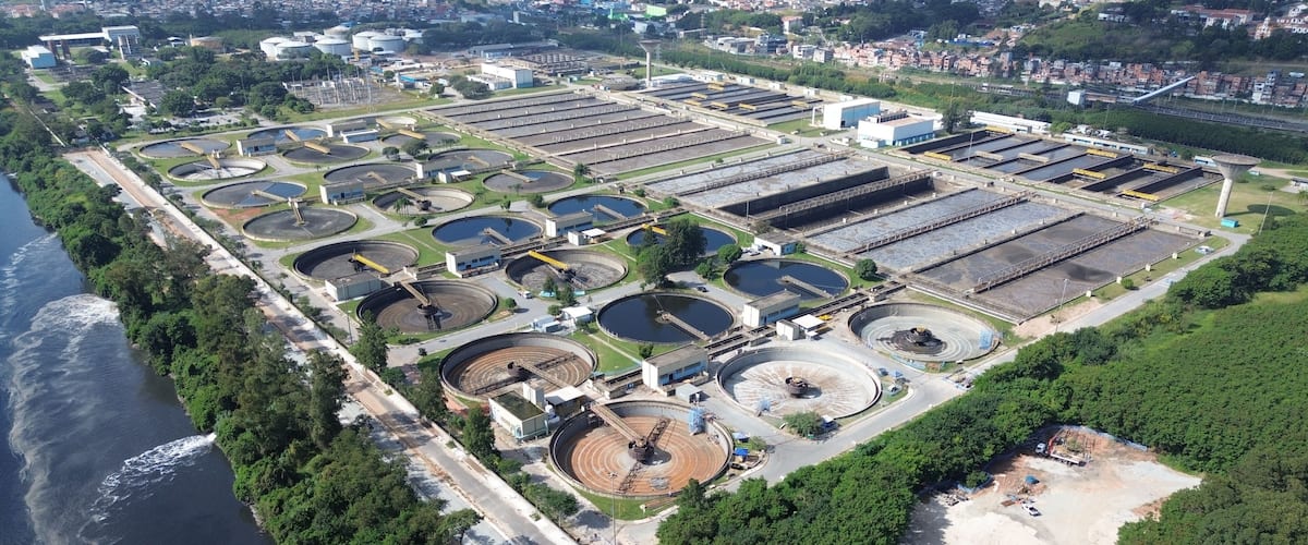An industrial complex with multiple circular tanks and rectangular structures, adjacent to a river.