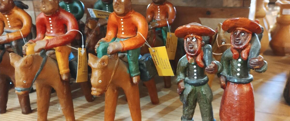 A collection of wooden figurines, some riding horses, others standing, with price tags.