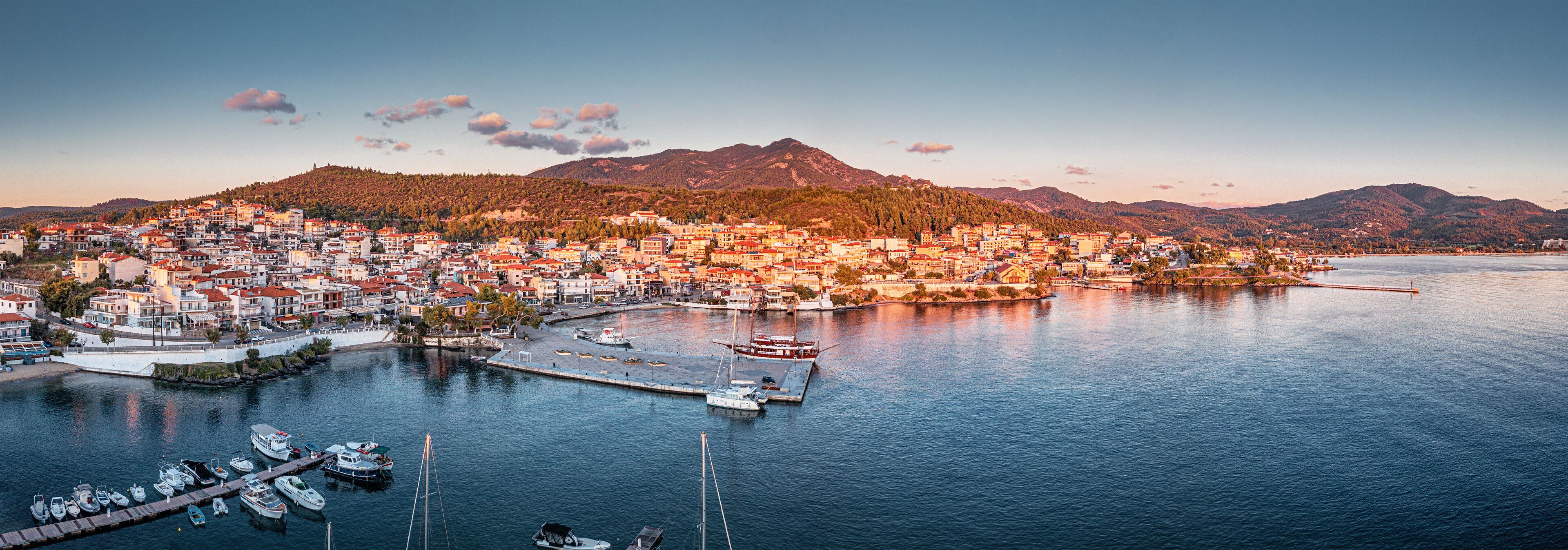 Aerial panorama of a scenic resort town Neos Marmaras with yacht marina sea port in Halkidiki, Sithonia. Majestic sunset time. Travel attractions and vacation in Greece
