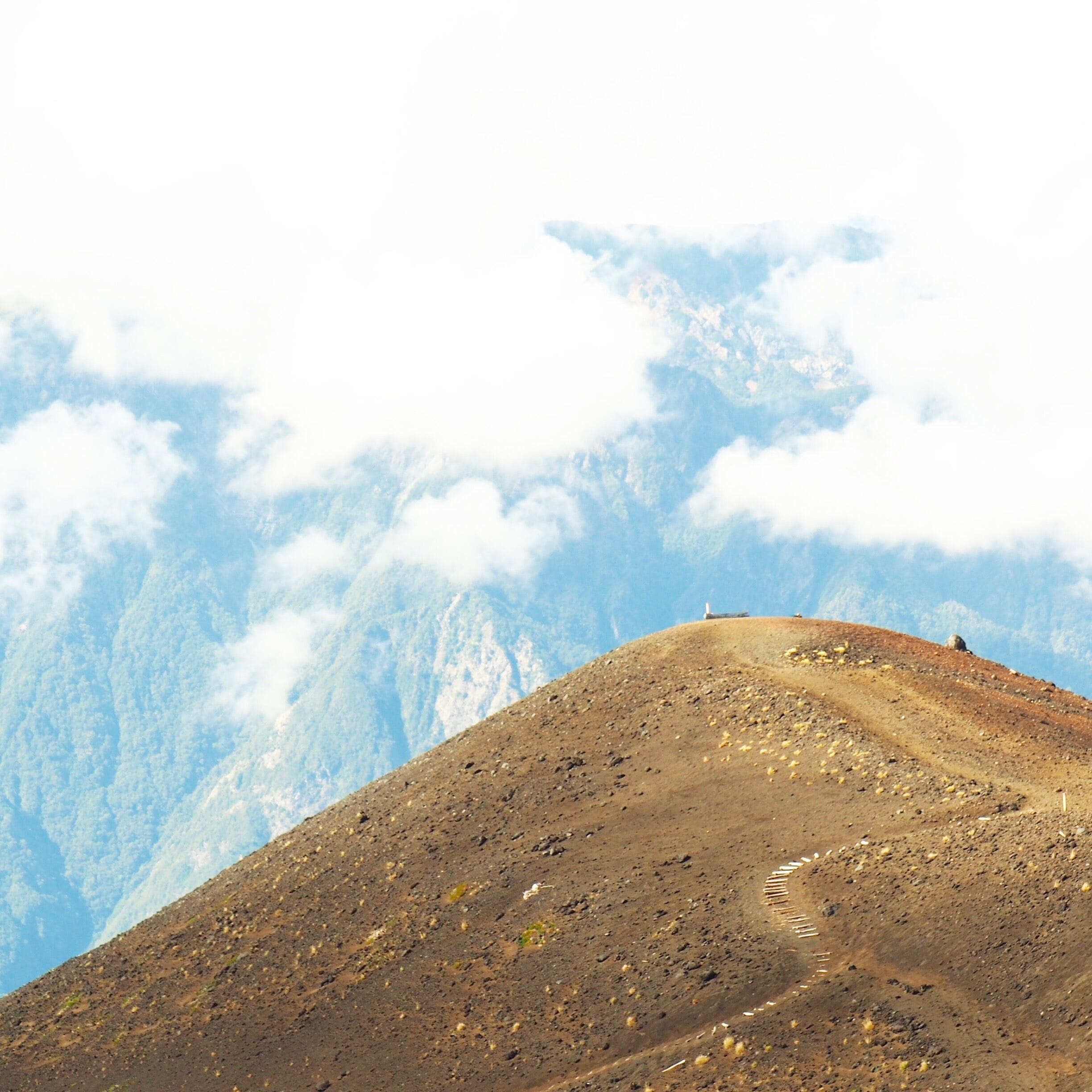 Volcan Osorno. It's a long winding road up to the summit.  Towards the volcano I can't see much.  The clouds seem low (or perhaps it's the fact that the peak is at 2600m above sea level) and most of what I see towards that side, I can't capture with my camera.  We've decided to take the chair lift up to its highest point - about 100m below the actual summit.  Even though it's early morning there is a buzz in the air and it looks like people are walking the hills.  Towards the opposite side of the volcano is this view - a glimpse of what the summit must be like on a clear day.
#blue #volcano