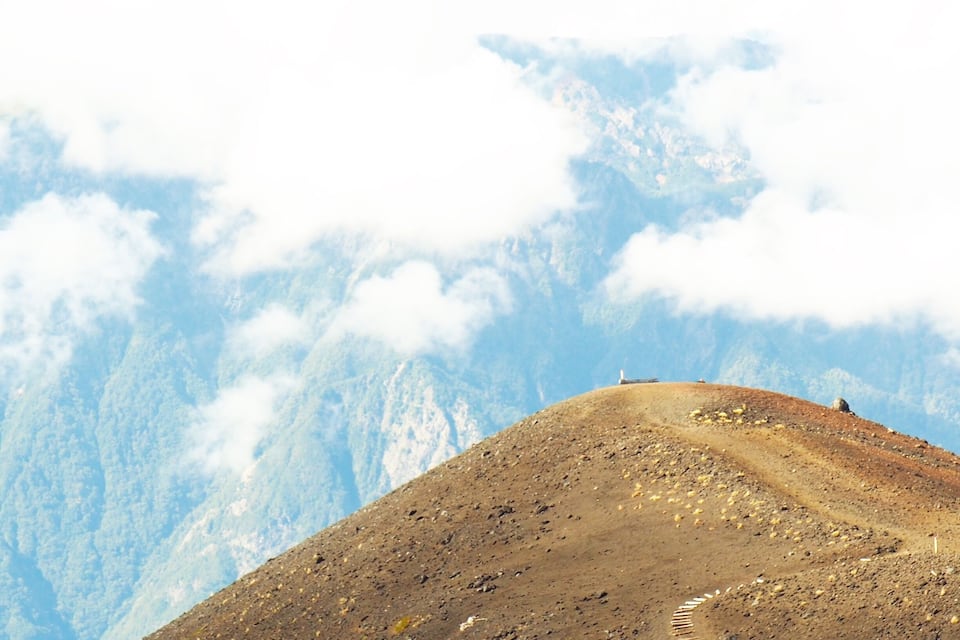 A mountain path with a rocky terrain and a clear sky.