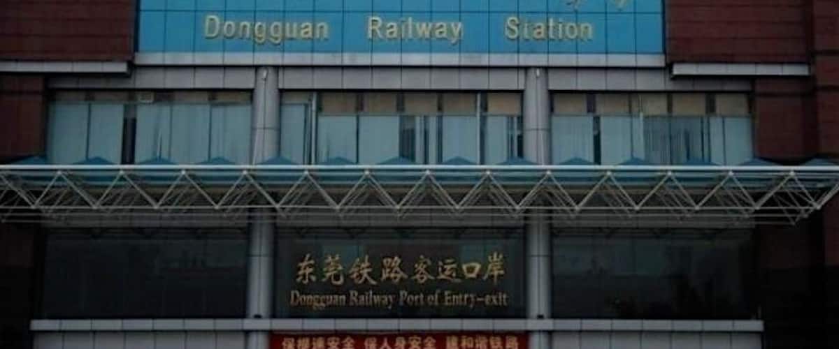 The exterior of Dongguan Railway Station with a blue facade and Chinese characters.