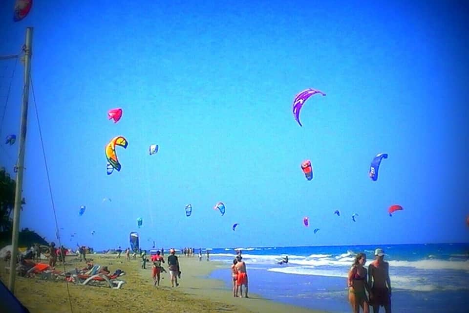 Una spiaggia con persone e aquiloni colorati che volano nel cielo.