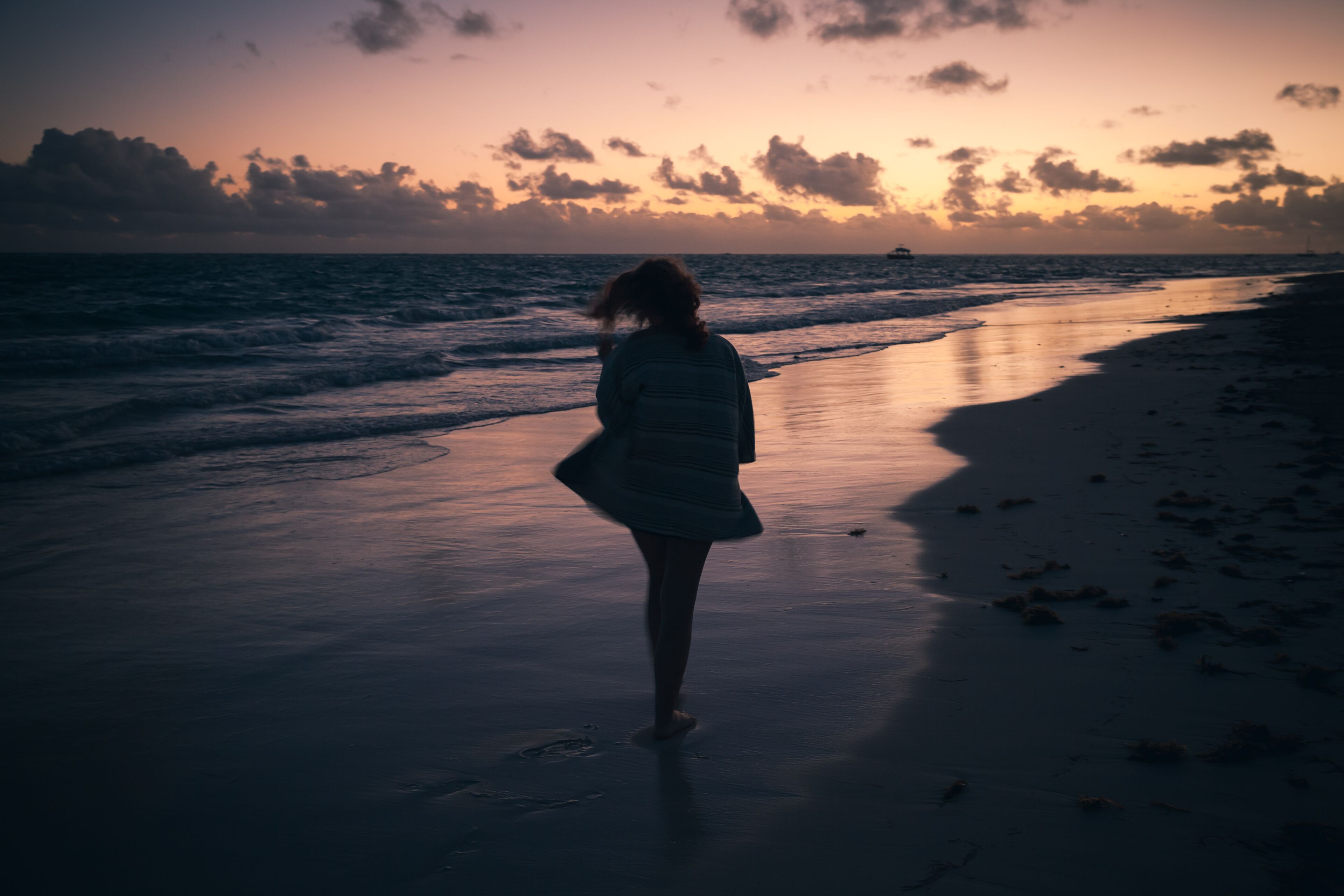 A person walking on a beach at sunset.