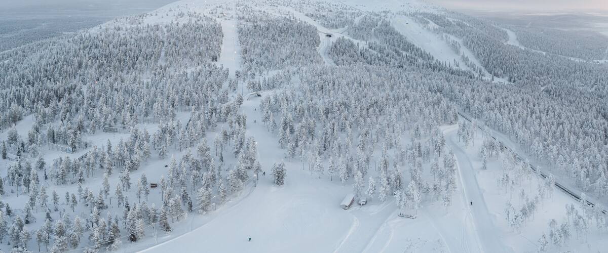 A snow-covered mountain with a ski trail and a train track.
