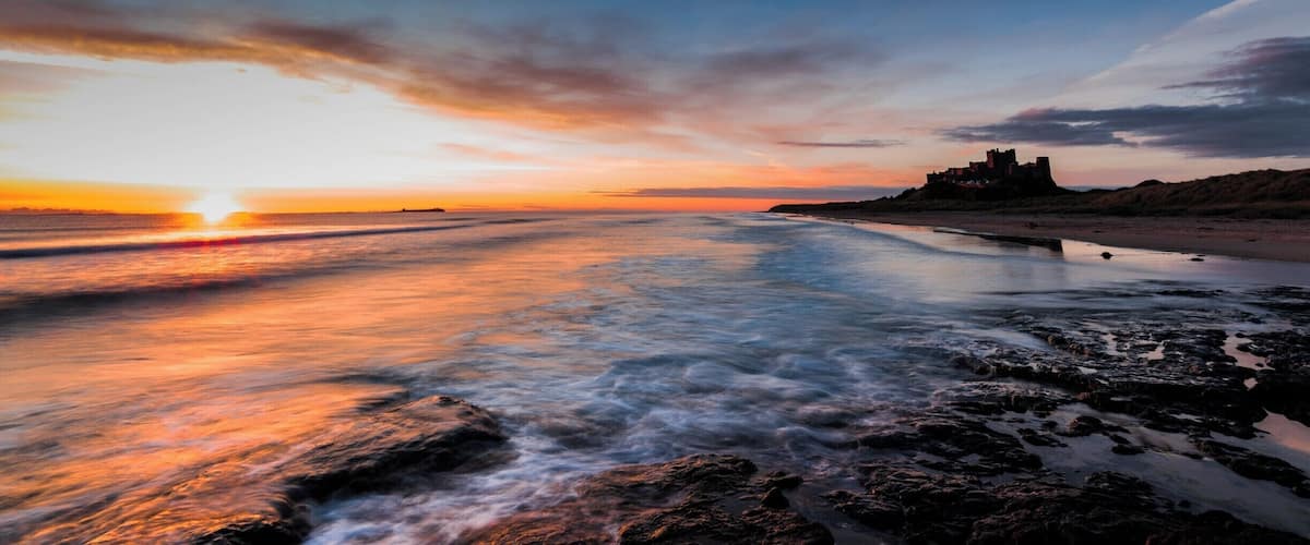 An early morning sunrise over the beach at Bamburgh Castle in Northumberland