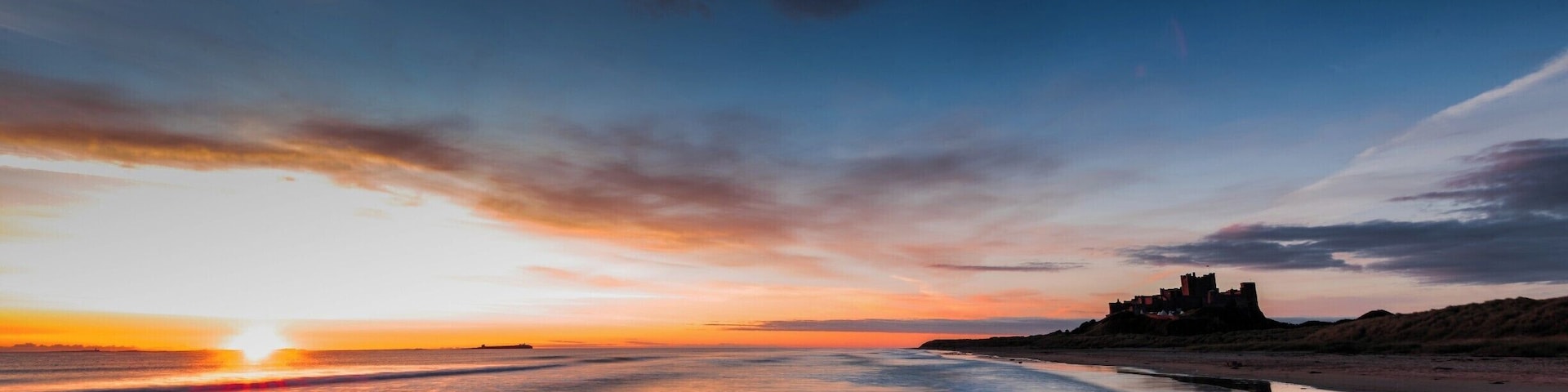 An early morning sunrise over the beach at Bamburgh Castle in Northumberland
