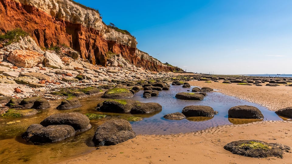 A rocky beach with clear water and large boulders.
