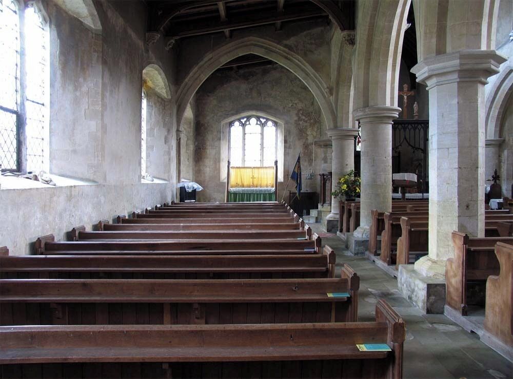 An empty church interior with wooden pews, arched ceilings, and stained glass windows.