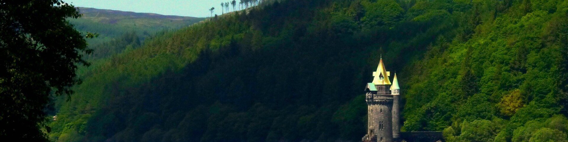 Una torre con un campanario dorado en una colina con vistas a un cuerpo de agua.