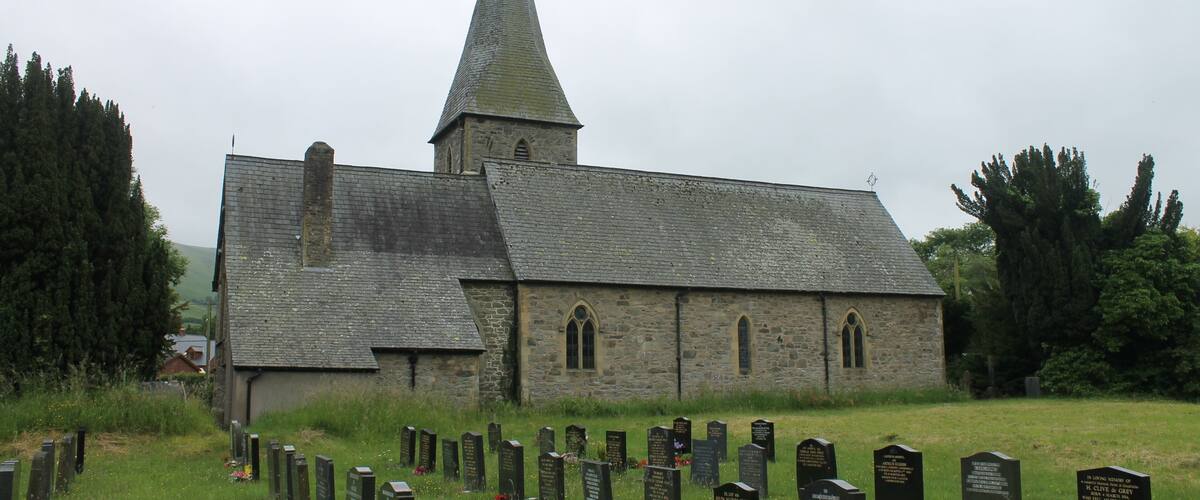 A church with a tall steeple and a graveyard in front.