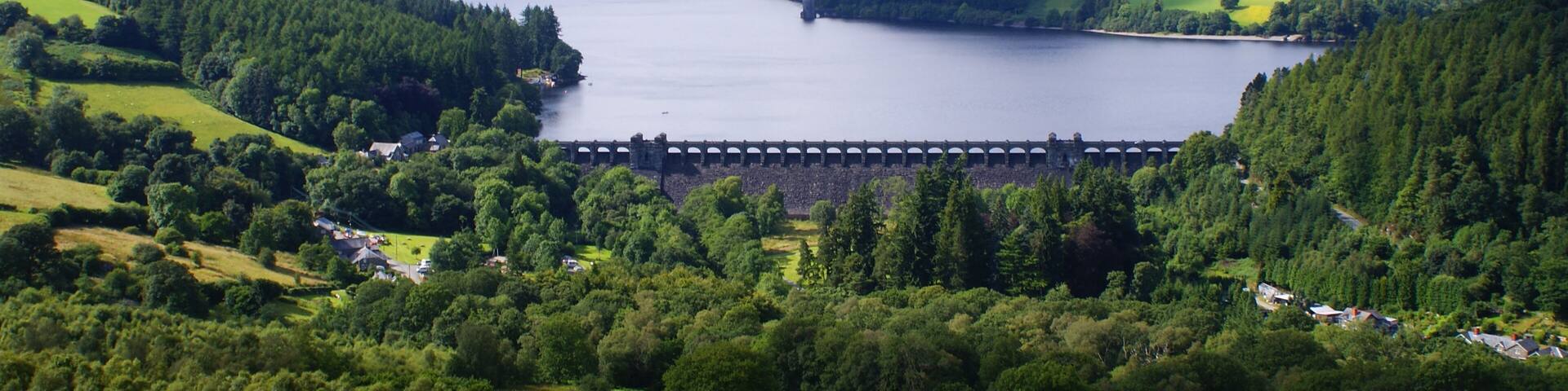 Lake Vyrnwy and Dam in Powys, Wales. From the summit of Craig garth-bwlch. Showing the village of Llanwddyn, much of the lake looking north west, the dam and the straining tower. This photo was taken on 25/07/09 at 16:23 by Sean Hattersley.