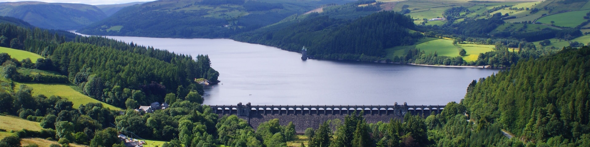 Lake Vyrnwy and Dam in Powys, Wales. From the summit of Craig garth-bwlch. Showing the village of Llanwddyn, much of the lake looking north west, the dam and the straining tower. This photo was taken on 25/07/09 at 16:23 by Sean Hattersley.