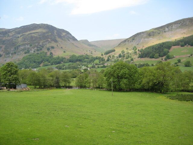 A green field with trees and hills in the background.