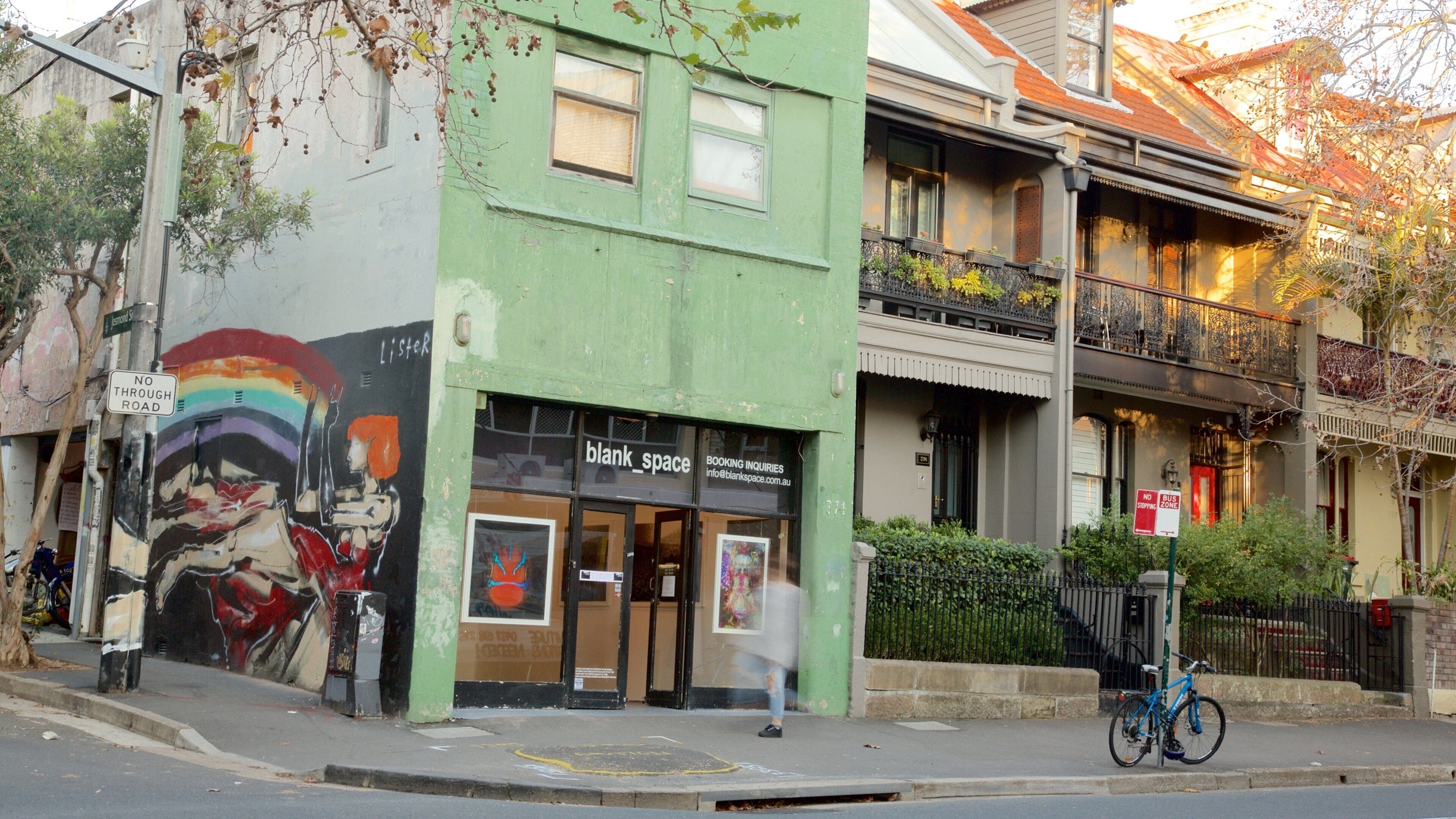 A green building with a mural, a sign for 'blank_space', and a bicycle parked outside.