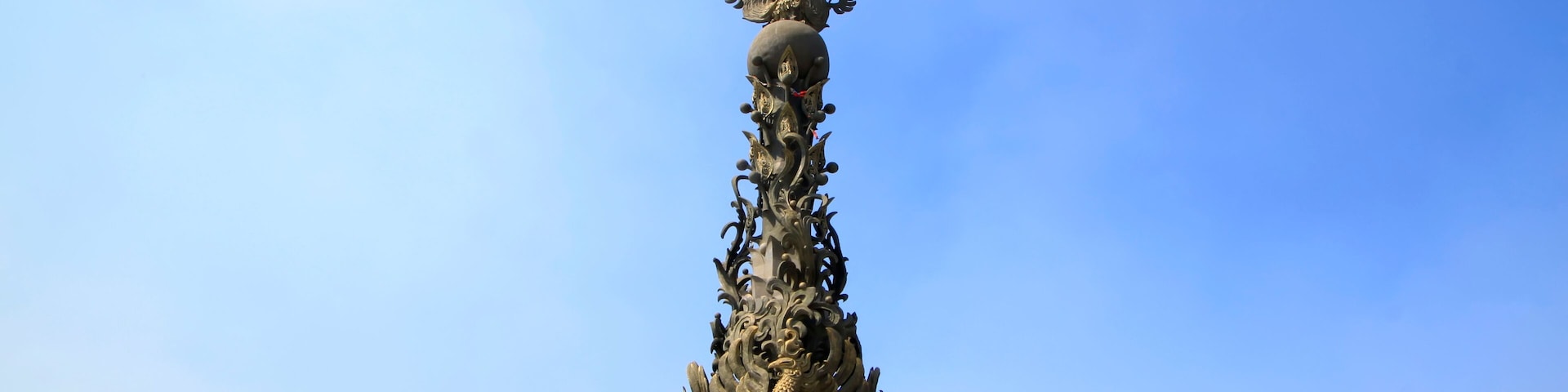 Um monumento alto e ornamentado, com desenhos elaborados e estátuas de leão na base.