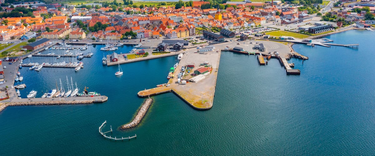A coastal town with a harbor, boats, and a castle-like structure.