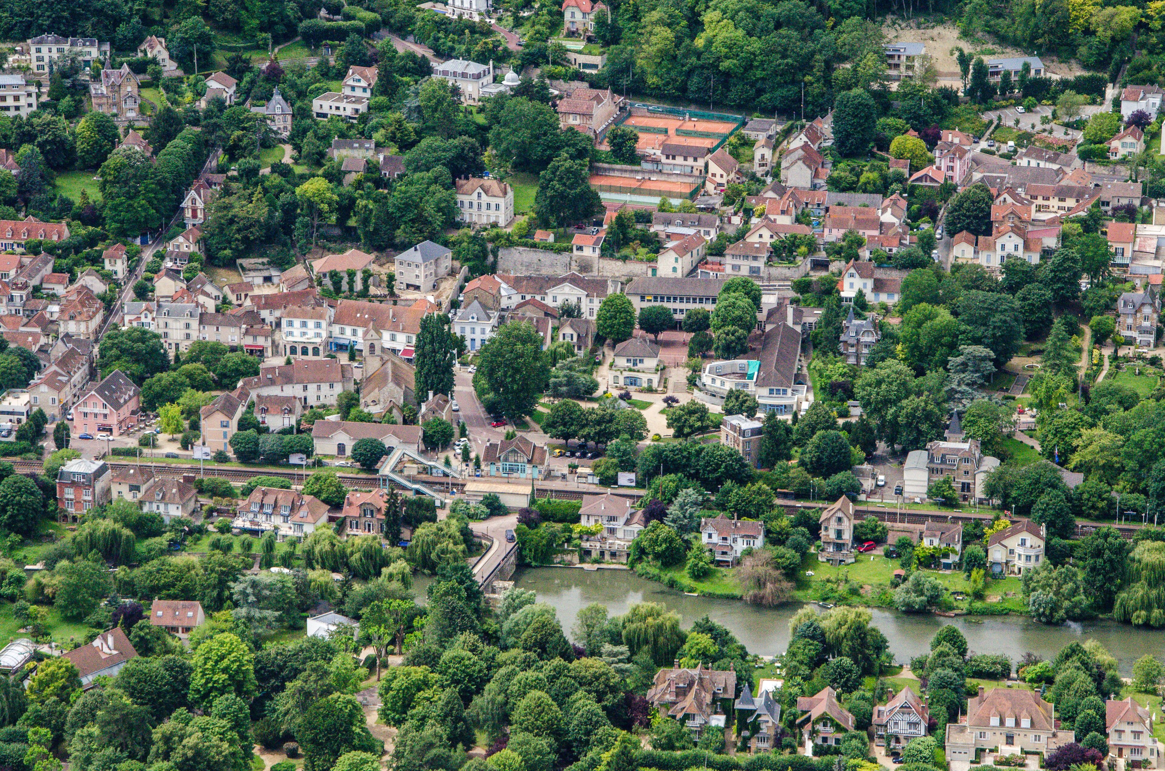 A densely populated residential area with houses, a river, and surrounding greenery.