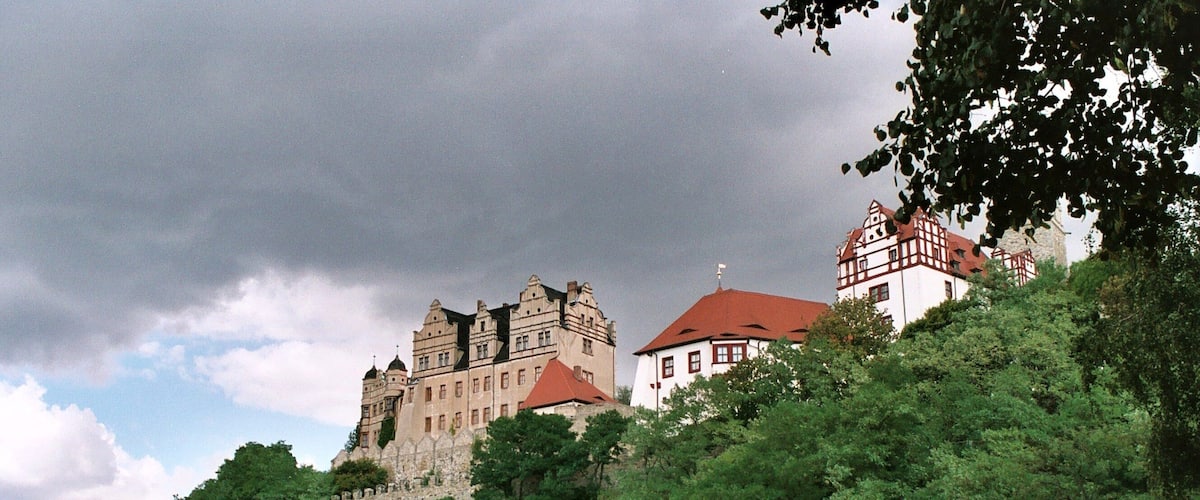 A castle on a hill with a bridge over a river.