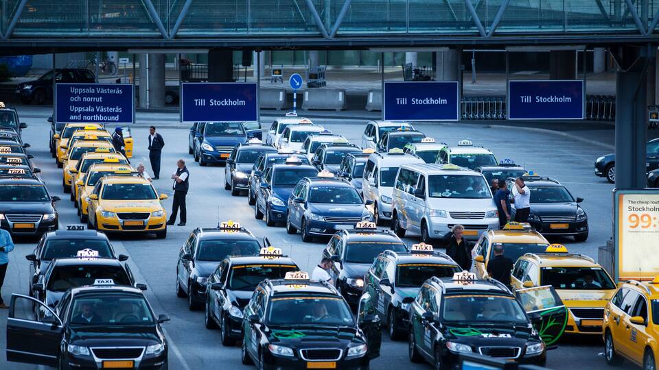 A busy traffic jam at an airport with multiple taxis and cars.