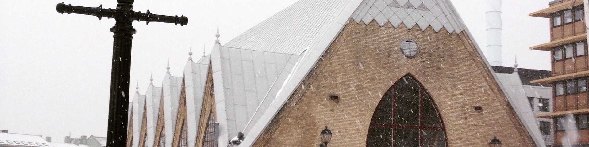 Un edificio cubierto de nieve con techo a dos aguas y una entrada arqueada grande.