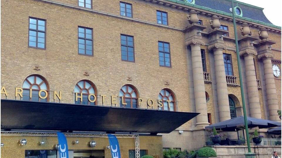 The exterior of the Arion Hotel Post with a classic architectural style, featuring a prominent entrance and a flag.