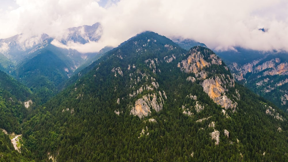 A mountainous landscape with dense forests and rocky cliffs.