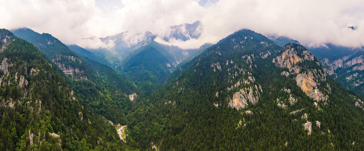 A mountainous landscape with dense forests and rocky cliffs.