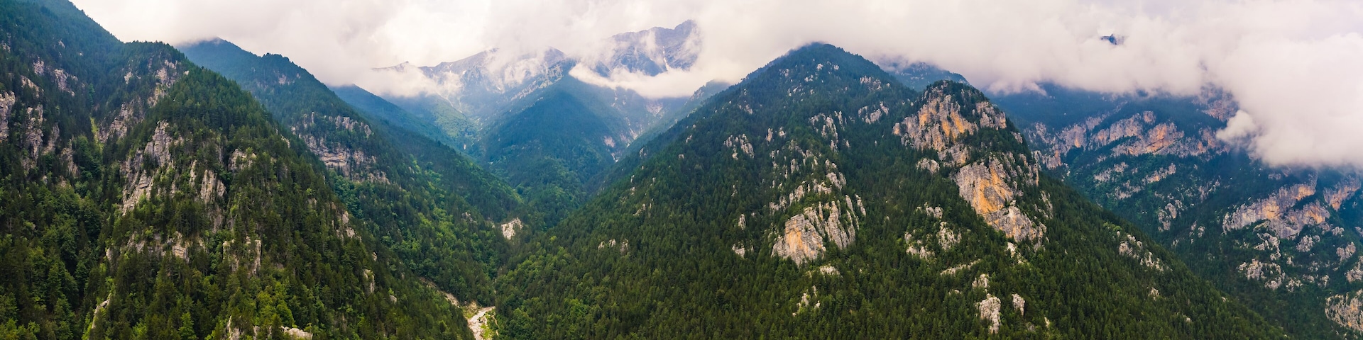 A mountainous landscape with dense forests and rocky cliffs.