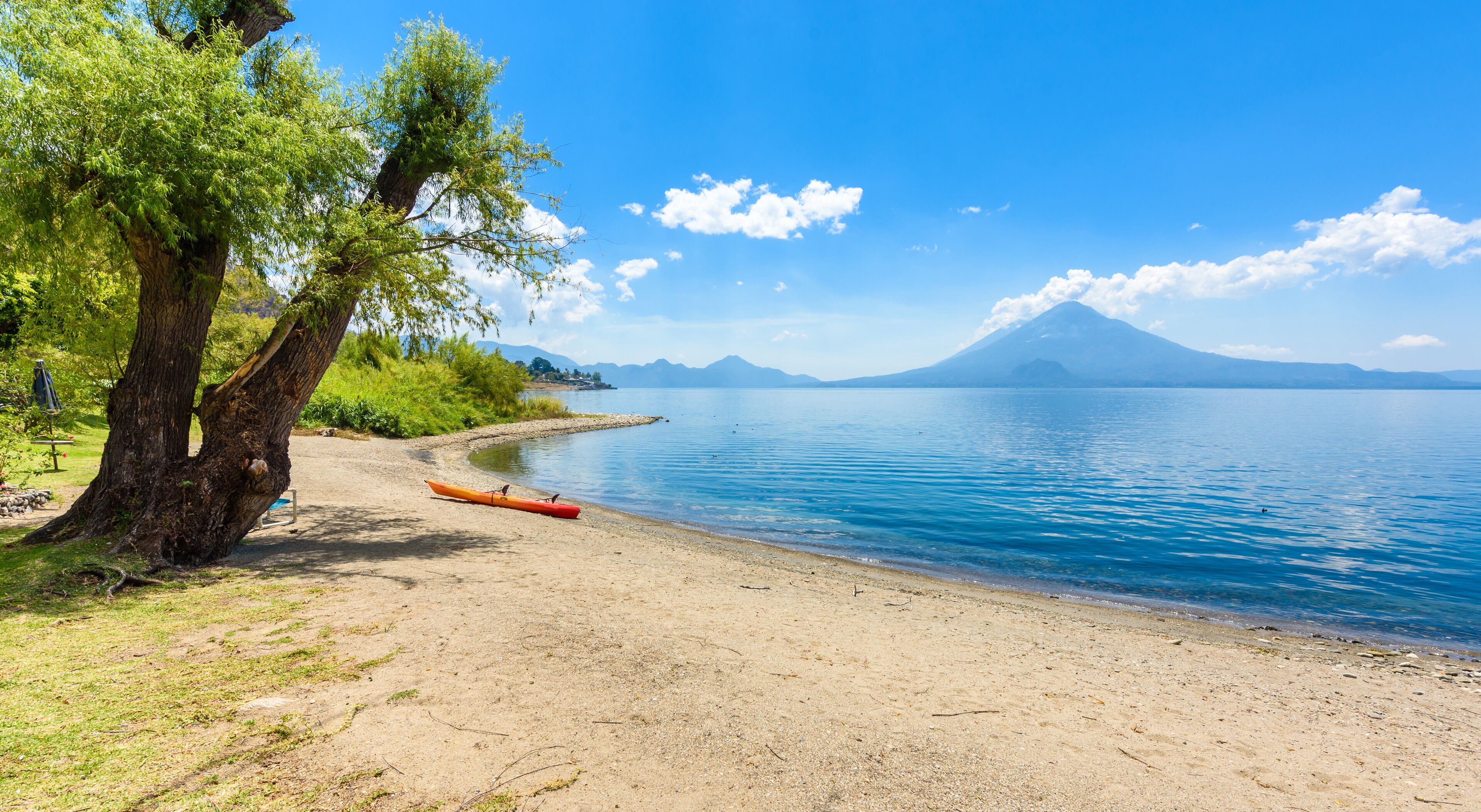 Paradise beach with chair and kayak at lake Atitlan, Panajachel - Relaxing and recreation at beach with vulcano landscape scenery in the highlands of Guatemala