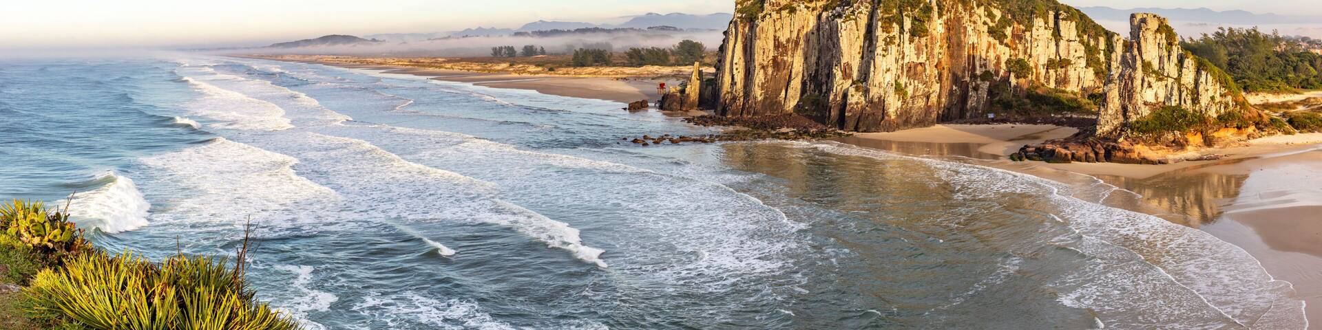 Guarita beach with waves, cliffs and winter fog over the trees