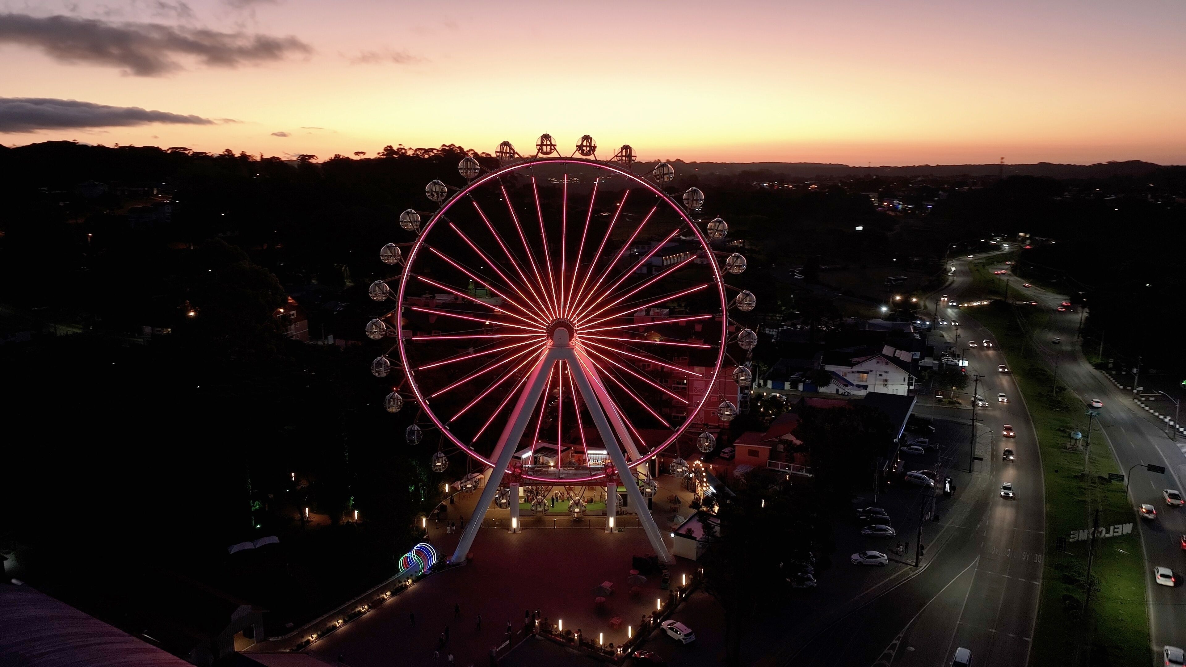 Illuminated Ferris Wheel At Canela In Rio Grande Do Sul Brazil. Colorful Ferris Wheel. Illuminated City. Sunset Landscape. Illuminated Ferris Wheel At Canela In Rio Grande Do Sul Brazil. 