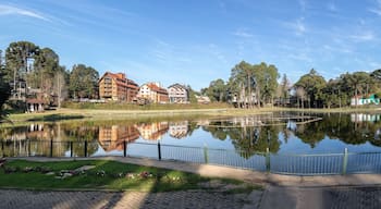 Un lago tranquilo con una cerca, rodeado de edificios y árboles.