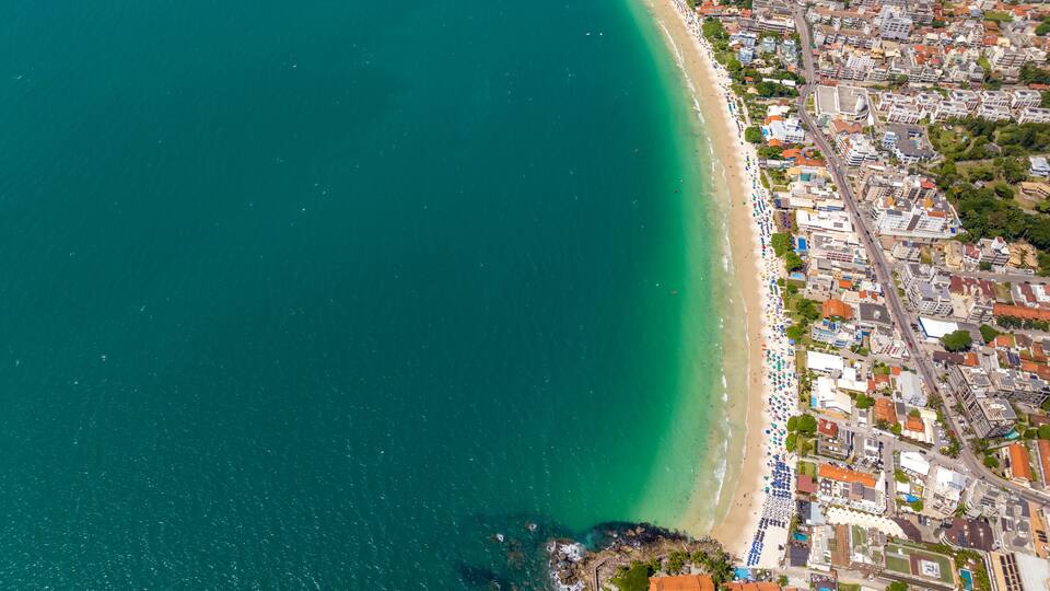 A coastal city with a beach, dense urban area, and clear turquoise waters.