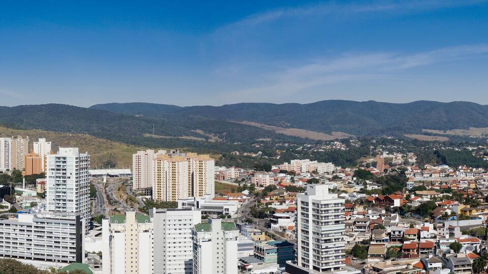 A cityscape with high-rise buildings and a mountainous backdrop.