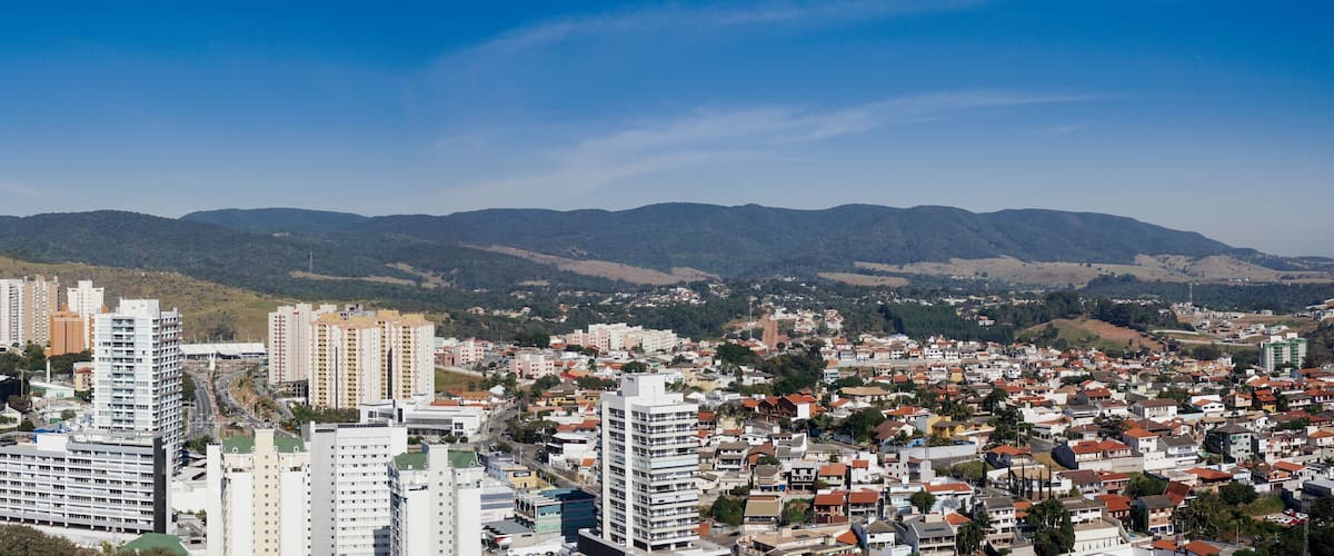 A cityscape with high-rise buildings and a mountainous backdrop.