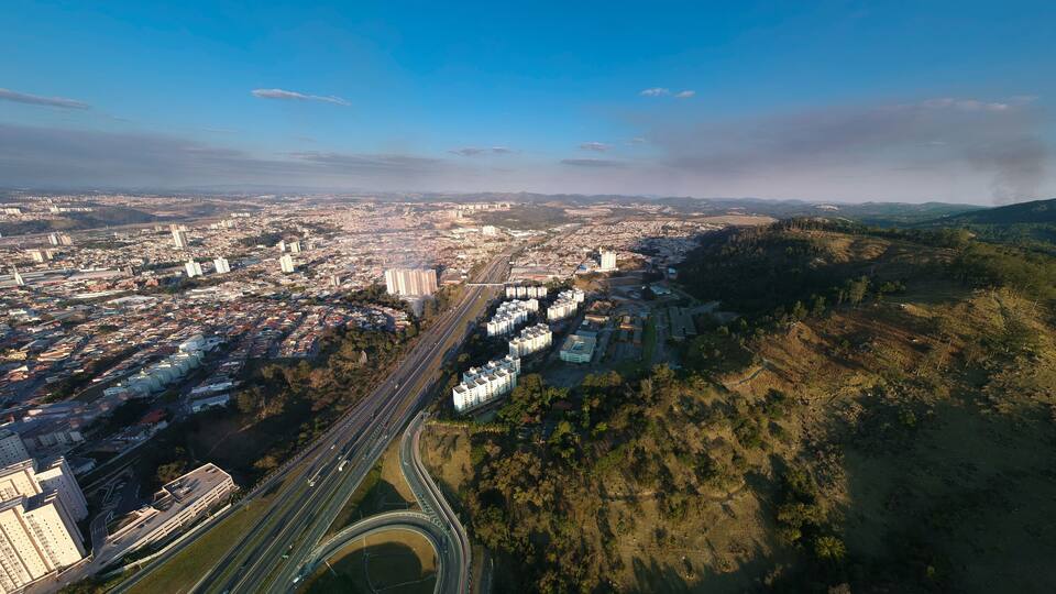 An aerial view of a city with a highway, buildings, and a hilly landscape.