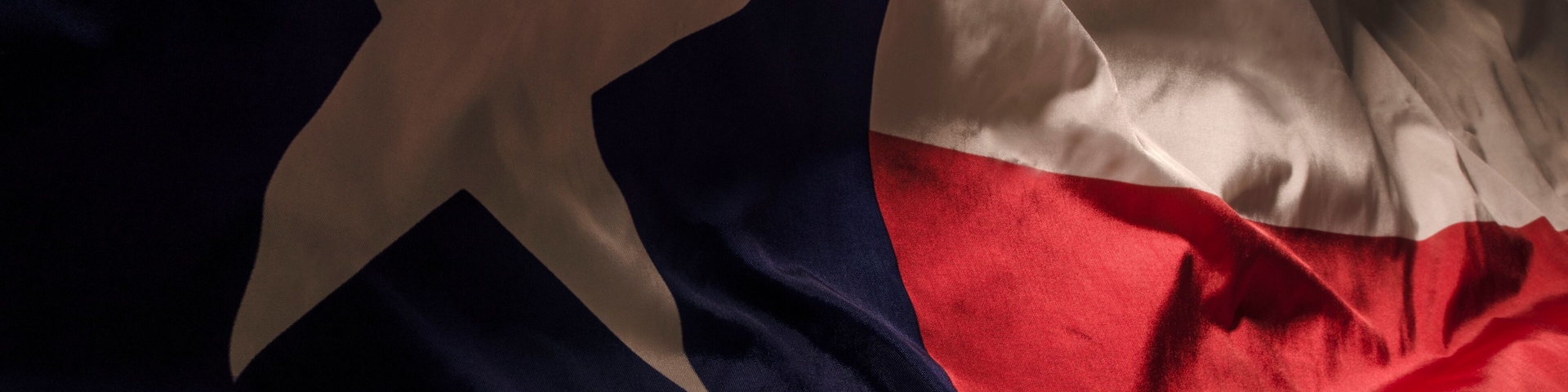 A close-up of a flag with a blue field, a white star, and a red and white cross.