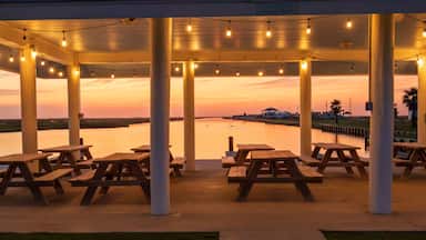 Um pavilhão à beira-mar com luzes de fada e mesas de piquenique.