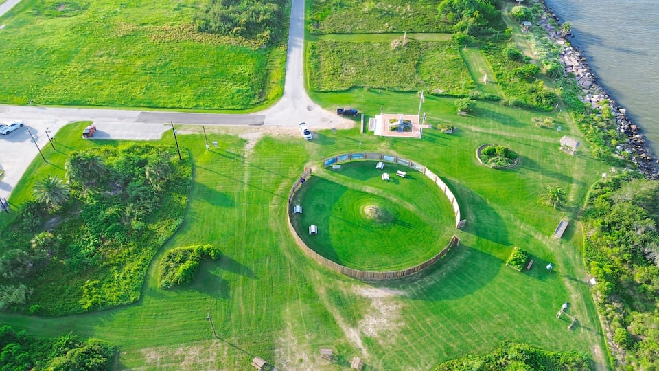 Unique circular structure sits within green park grounds near coastal jetty navigation channel. This site offers space for visitors overlooking maritime transit corridor, Freeport, TX