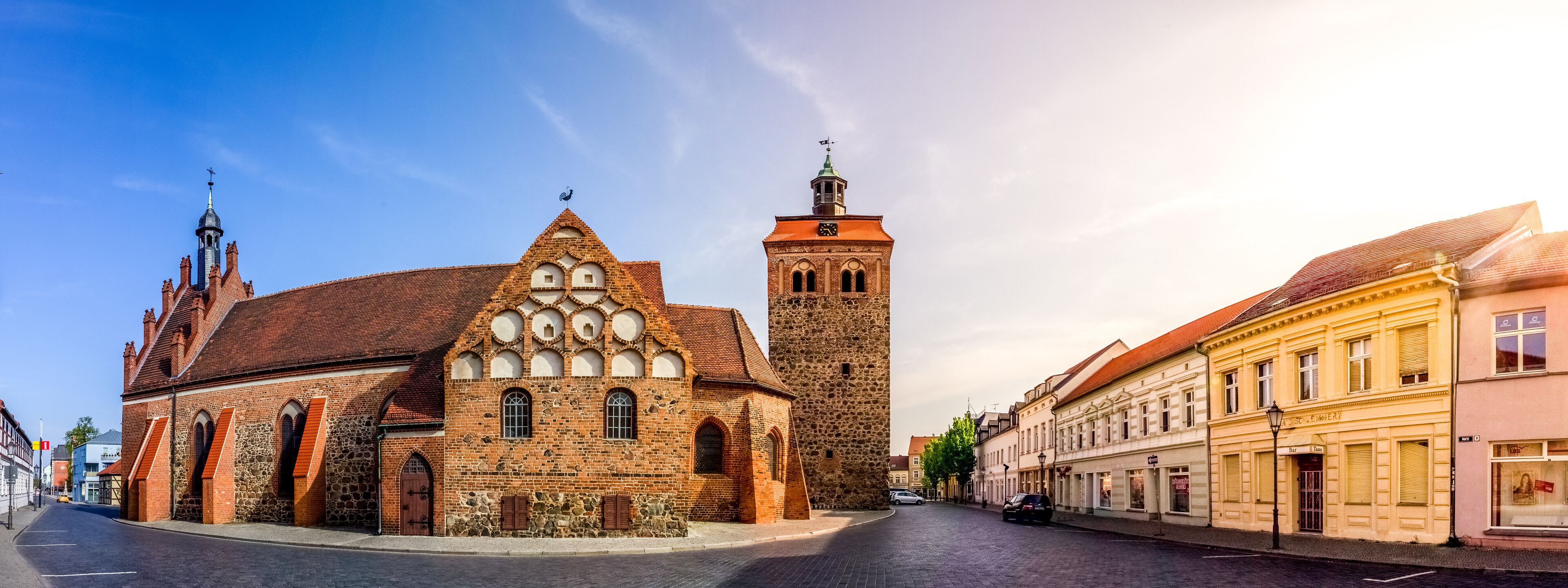 A historic church with a prominent tower and a stone building with arched windows.