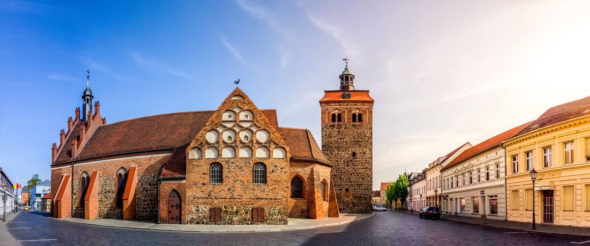 A historic church with a prominent tower and a stone building with arched windows.