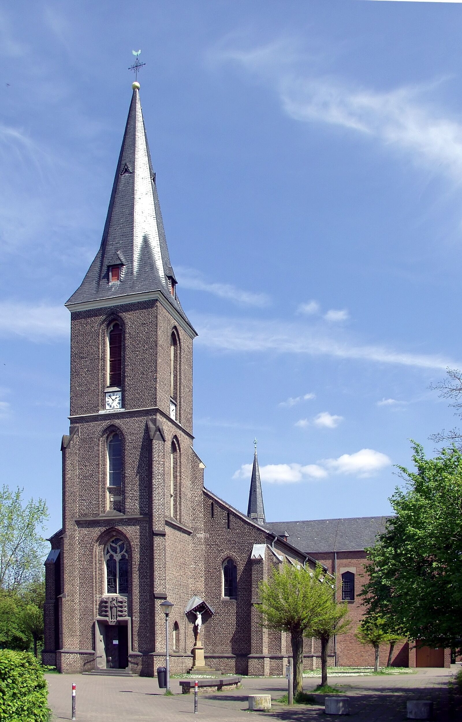 A brick church with a tall steeple and a smaller spire.