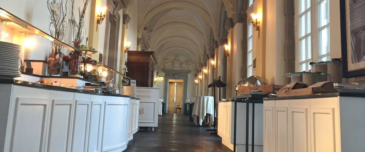 A grand hall with high ceilings, arched windows, and ornate wall decorations.